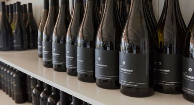 Several Lunessence red wine bottles lined up on a white shelf