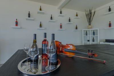 Bottles of wine and glasses on a silver tray next to a violin