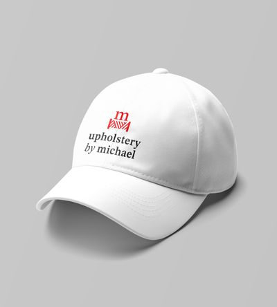 Mockup of white cap with Upholstery By Michael logo printed in red and charcoal