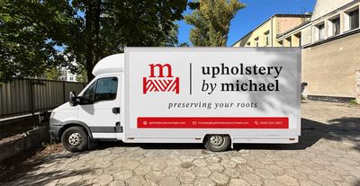 White box truck with Upholstery By Michael logo decal, including tagline and contact information